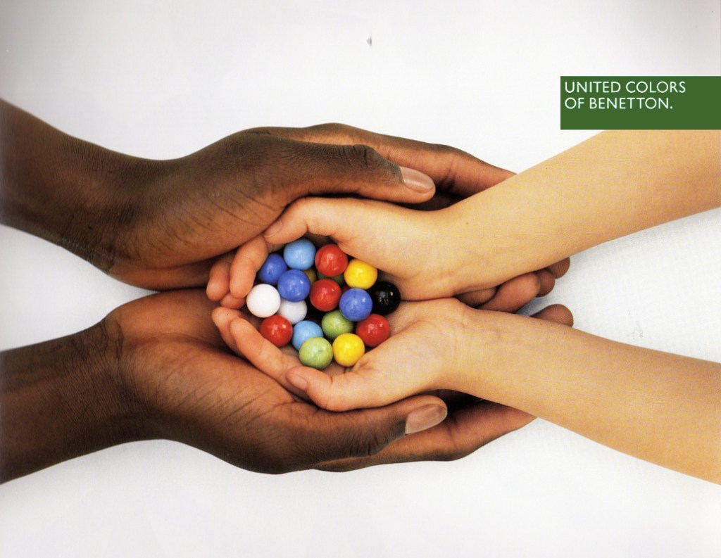 Publicité Benetton - United colors of Benetton — Oliviero Toscani - Mains blanches tenant des bonbons colorés dans mains noires - 1990