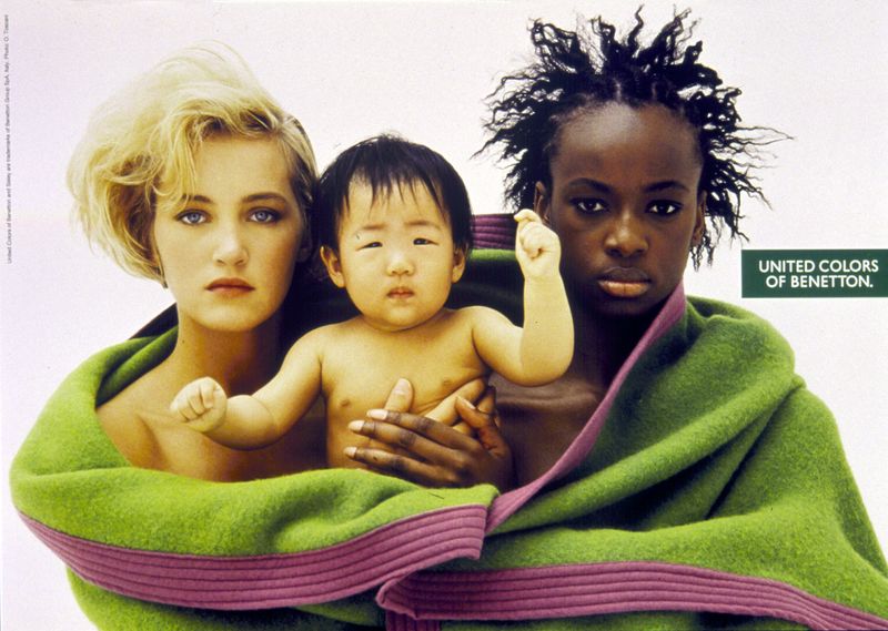 Publicité Benetton - United colors of Benetton — Oliviero Toscani - Femme blanche et femme noire avec un enfant asiatique dans une couverture verte  - 1990