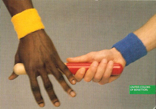 Publicité Benetton - United colors of Benetton — Oliviero Toscani - Main blanche passe le témoin à une main noire - 1990