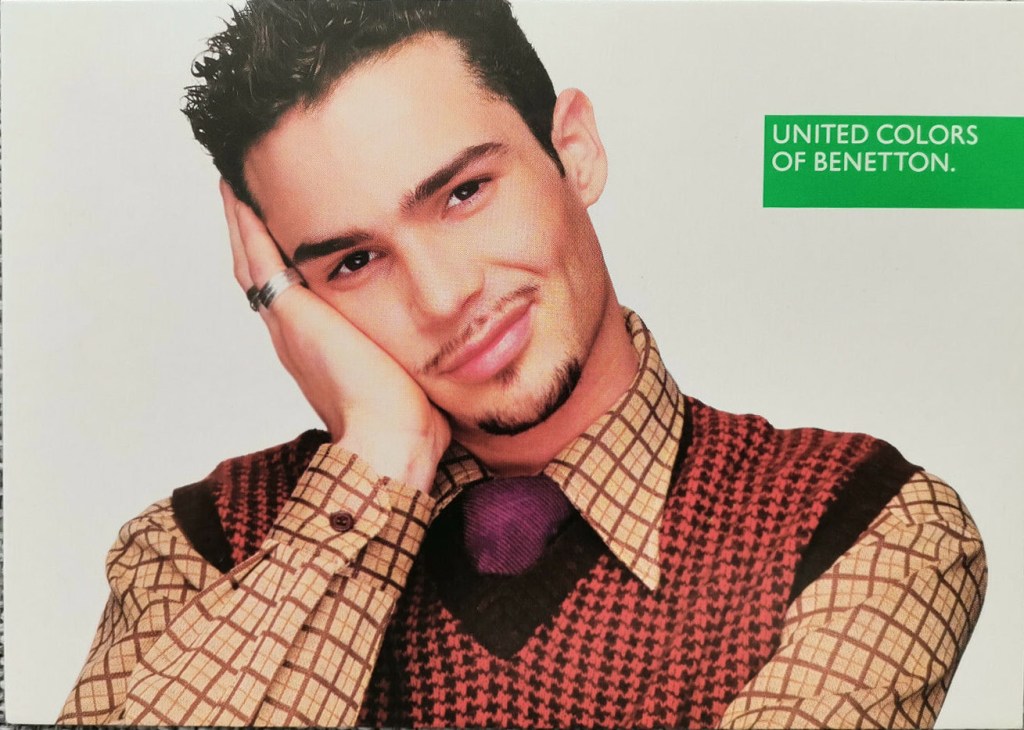 Publicité Benetton - United colors of Benetton - Oliviero Toscani - Homme souriant, tenant son visage dans sa main avec chemise et pull très coloré