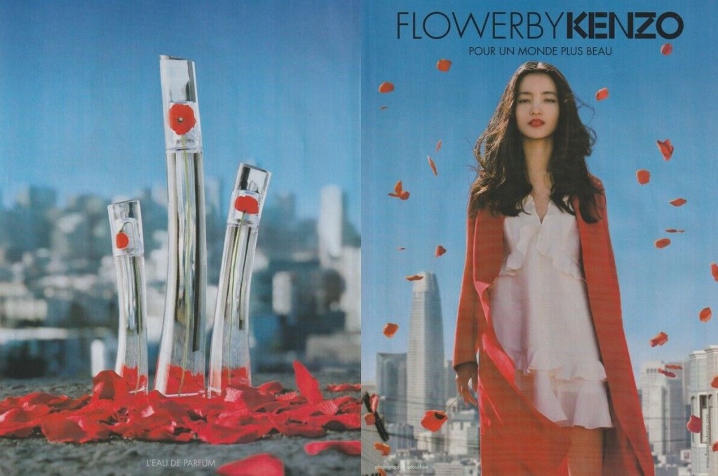 Publicité Kenzo -  Flower by Kenzo - Pour un monde plus beau - À gauche, 3 packagings, au fond une ville - À droite, femme s'avançant devant un décor urbain - Double page - 2018