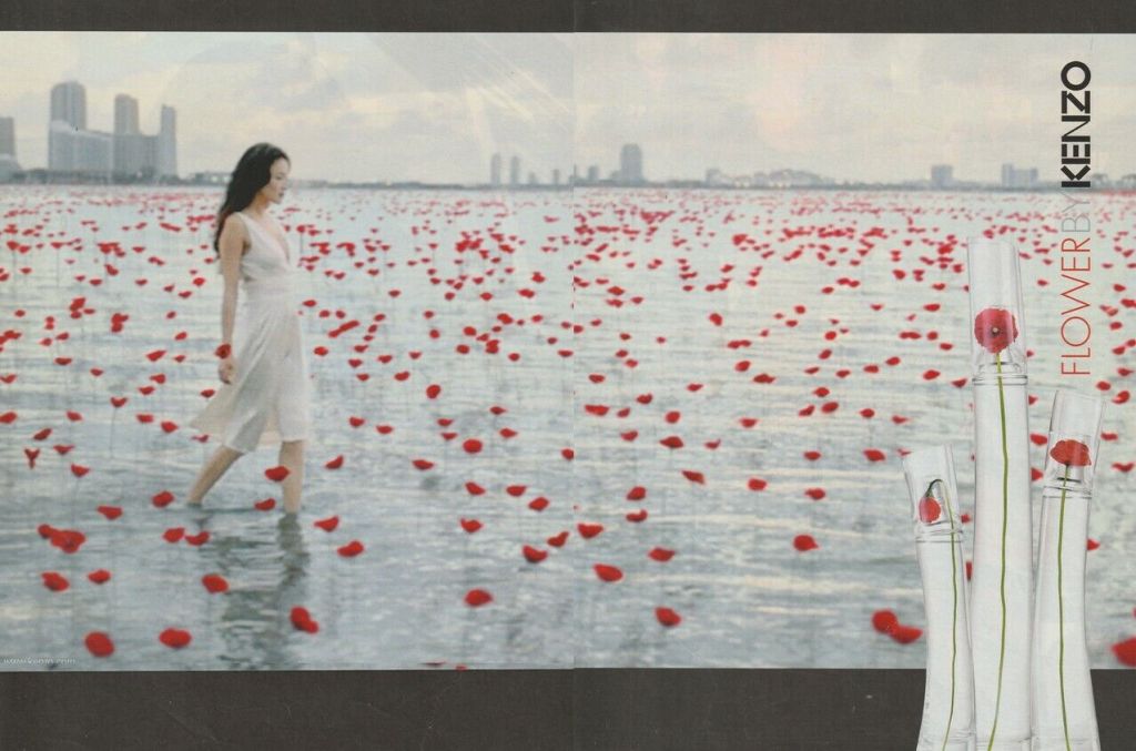 Publicité Kenzo -  Flower by Kenzo - Coquelicots sur une étendue d'eau - 3 flacons sur le côté - Femme en blanc marchant au milieu