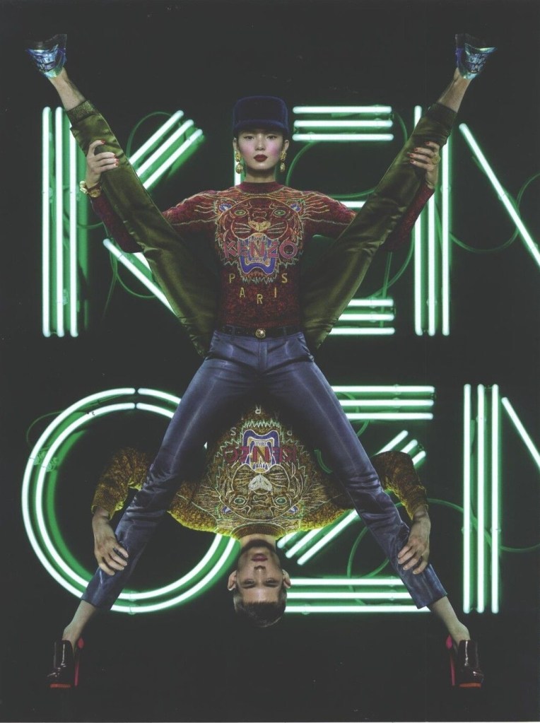 Publicité Kenzo - Prêt à porter - Un homme et une femme forment un X en tenues très colorées sur fond orange - 2013