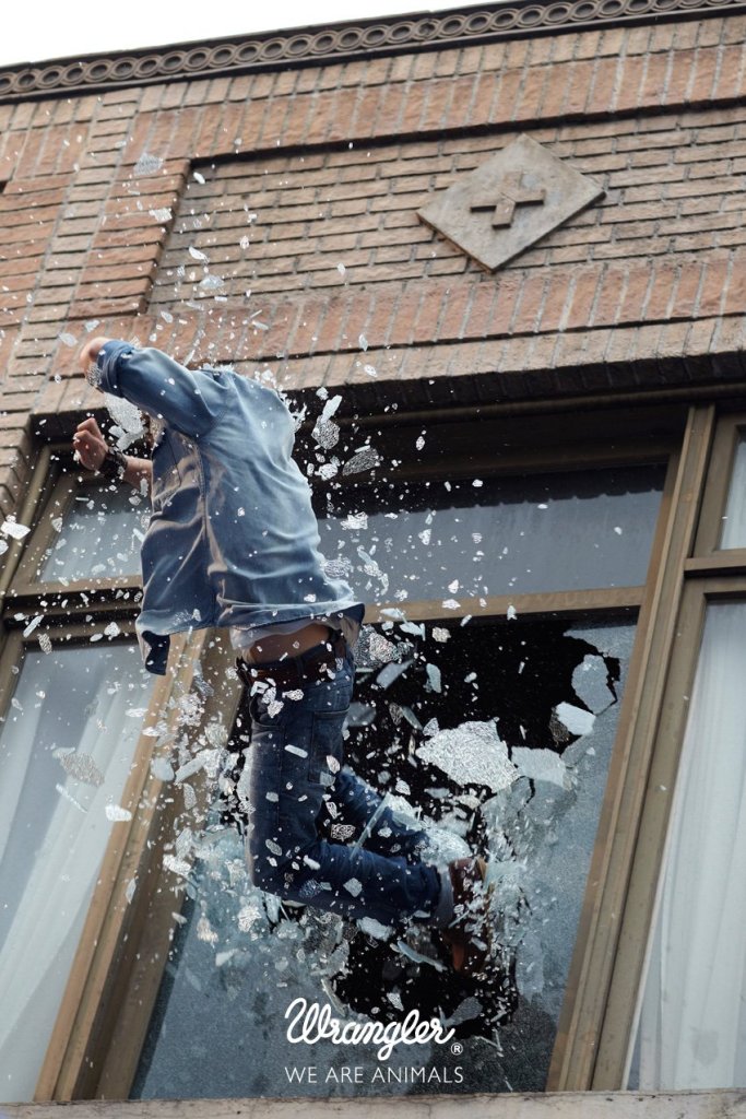 Publicité Wrangler - We are animals - Stunt - Un homme en chemise bleu clair traverse une fenêtre - Agence Fred&Farid - France - Photographe Cass Berd