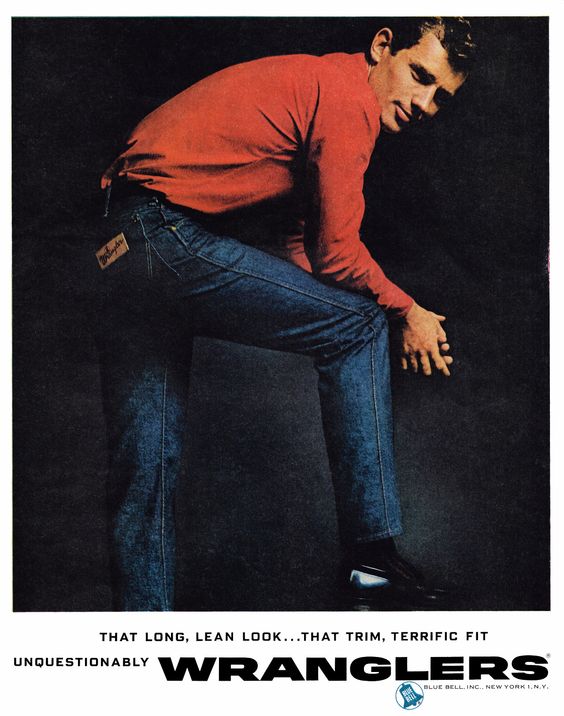 Publicité Wrangler - Jeans - That long, lean look... that trim, terrific, fit inquestionably - Un homme en sweat rouge penché vers l'avant regarde l'objectif en souriant - USA - 1961