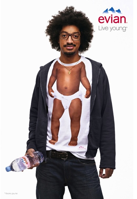 Publicité evian - Live Young - Baby Inside - Tee-shirts bébé - Homme métis en sweat gris foncé tient une bouteille à la main droite - Agence BETC EuroRSCG Paris - 2010