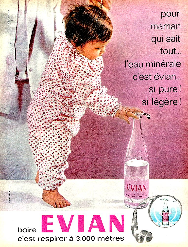 Publicité EVIAN - Boire EVIAN, c'est respirer à 3000 mètres - Bébé tenu par sa mère de la main, touchant la bouteille d'Évian avec des doigts - 1962