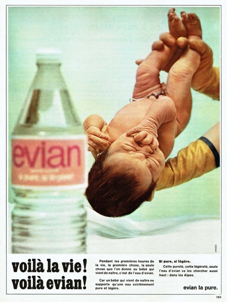 Publicité evian - Voilà la vie ! Voilà evian ! - Bouteille floue au premier plan et mains de sage-femme tenant un enfant naissant - Agence Synodis - 1972