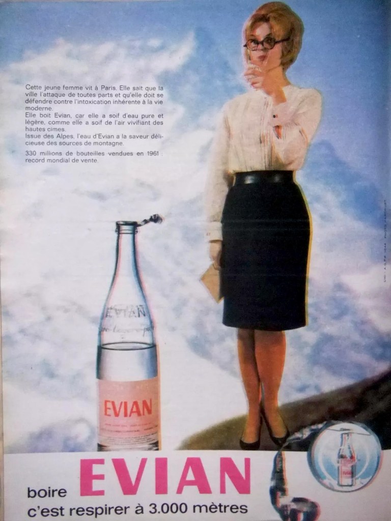 Publicité EVIAN - Boire EVIAN, c'est respirer à 3000 mètres - Femme à lunettes en train de boire dans un décor alpestre - 1962
