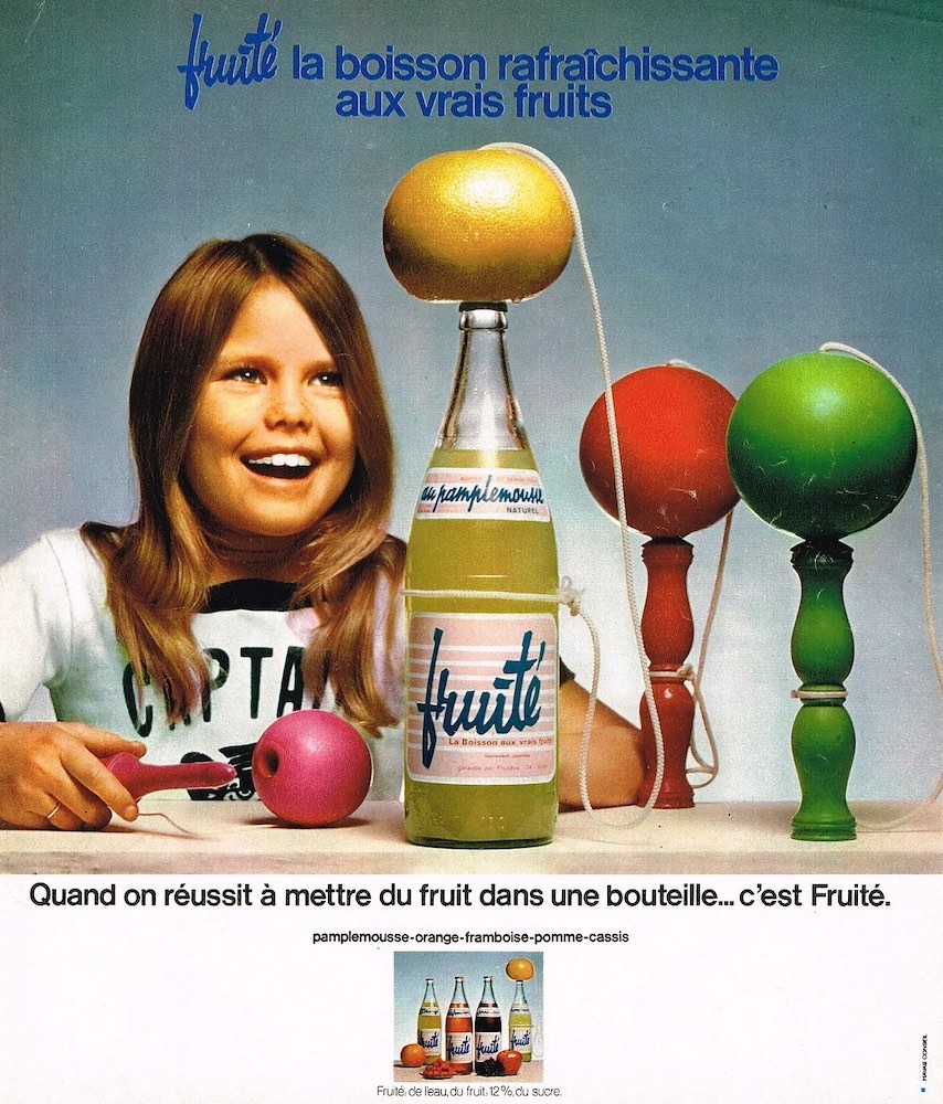 Publicité evian Fruité - Fruité, la boisson rafraîchissante aux vrais fruits - Jeune fille regardant un fruit au-dessus d'une bouteille - Analogie au bilboquet - 1973
