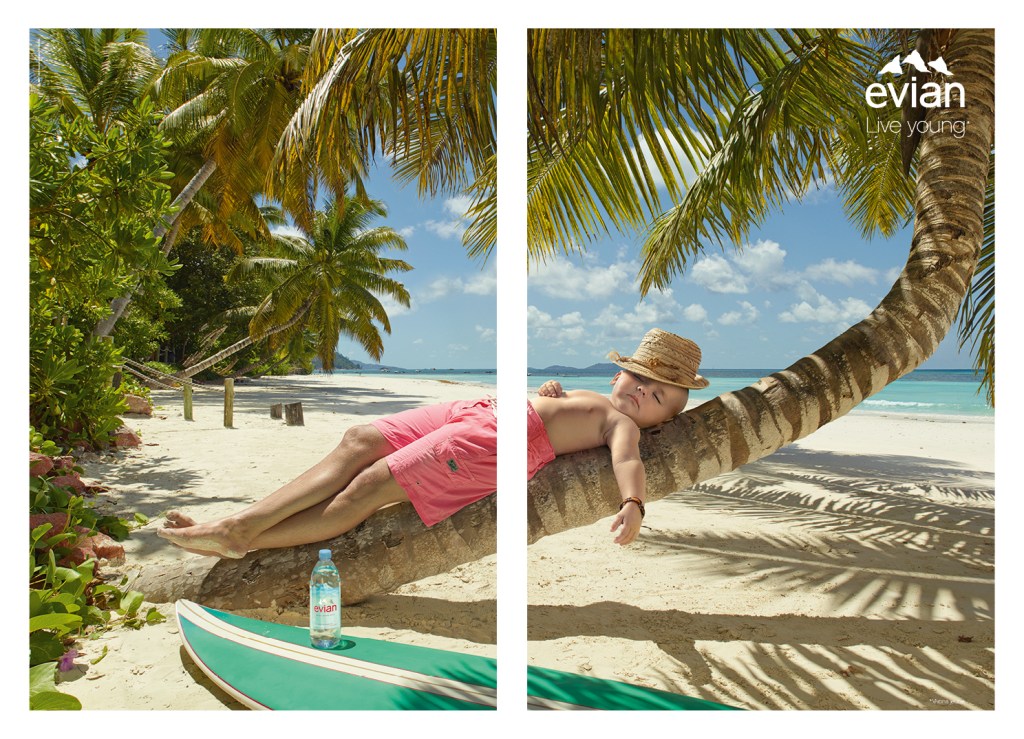 Publicité evian - Live Young - Little big baby - Affiche partagée avec l'homme d'un côté et sa version enfant de l'autre - Scène de farniente sur le tronc d'un palmier - Agence BETC - 2015