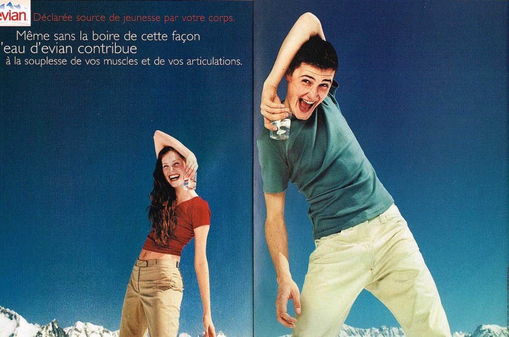 Publicité evian - Déclarée source de jeunesse par votre corps - contribue à la souplesse de vos muscles et de vos articulations - Couple de jeunes tenant leur verre d'eau de manière étrange - Décor alpestre - Agence BETC EuroRSCG - 2000