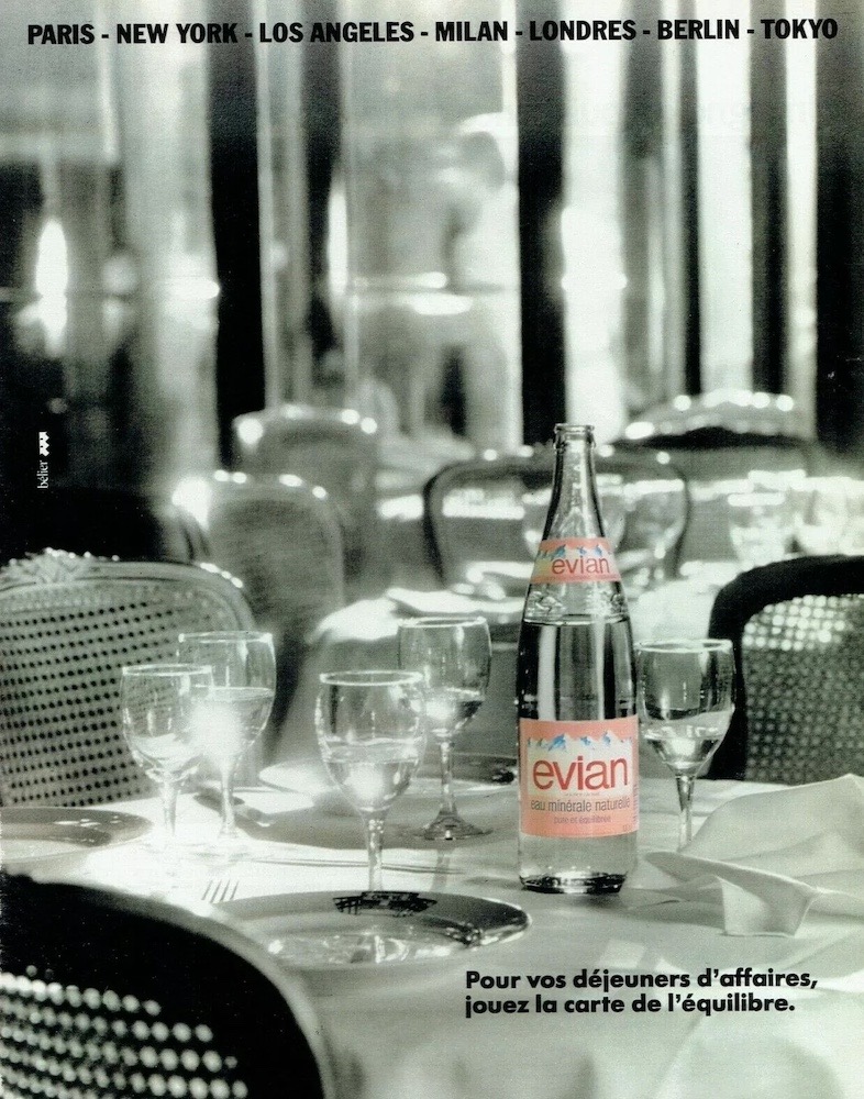 Publicité evian - Pour vos déjeuners d'affaires, jouez la carte de l'équilibre - Bouteille en couleur au milieu d'un décor de restaurant en noir et blanc - 1988