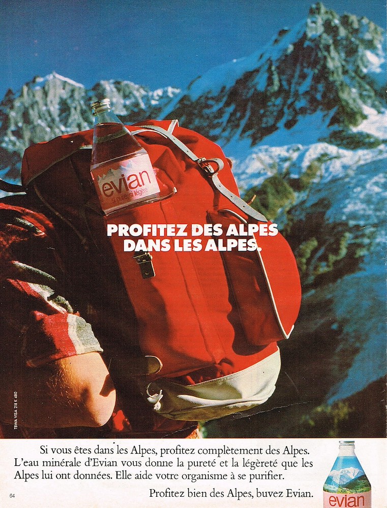 Publicité evian - Profitez des Alpes, buvez evian - Profitez des Alpes dans les Alpes - Un homme a mis une bouteille dans son sac à dos rouge - décor alpestre - Agence TBWA - 1979