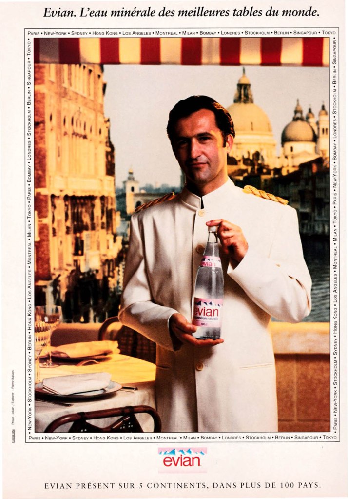 Publicité evian - L'eau minérale des meilleures tables du monde - Un serveur présente la bouteille en verre devant un décor vénitien - Évian présent sur 5 continents, dans plus de 100 pays - Agence Eurocom - 1993