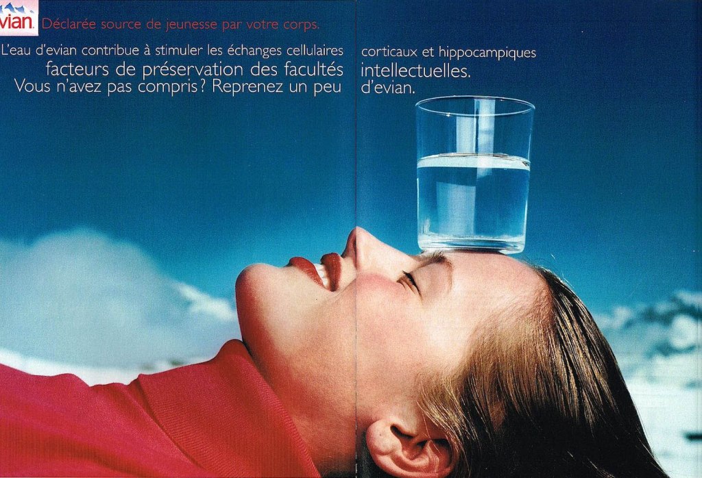 Publicité evian - Déclarée source de jeunesse par votre corps - Facteur de préservation des facultés intellectuelles - Jeune femme faisant tenir un verre en équilibre sur son front - Décor alpestre - Agence BETC EuroRSCG - 2000
