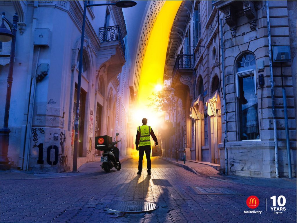 Publicité McDonald's - McDelivery - 10 ans - Une lumière jaune reprenant l'un des éléments du logo McDonald's vient éclairer le livreur debout avec le sac à la main de dos - Agence TBWA - Chypre - 2014