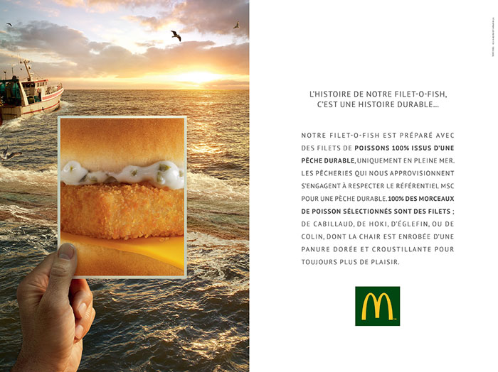 Publicité McDonald's - Histoires - L'histoire de notre filet-o-fish. C'est une histoire durable. - Une main tient une photo d'un filet-o-fish en gros plan devant la mer sur laquelle navigue un bateau sur fond de coucher de soleil - Agence TBWA Paris - 2014