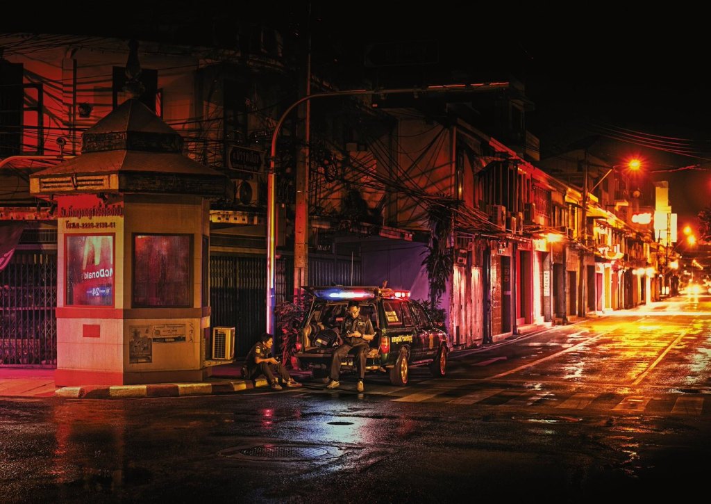 Publicité McDonald's - 24/24h - Reflets -  Un policier seul à l'arrière de sa voiture est sur son téléphone la nuit - Le logo de la marque se reflète sur une guérite - TBWA/DANThailand - Thaïlande - 2017