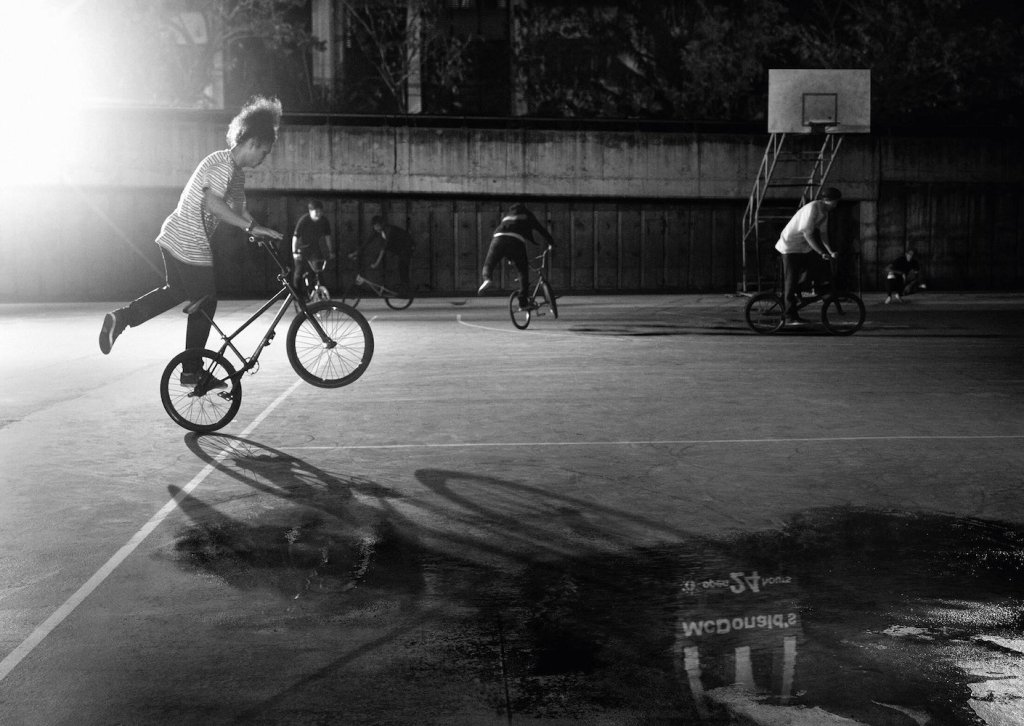 Publicité McDonald's - 24/24h - Reflets - Photo noir&Blanc - Des jeunes la nuit font du bicross sur un terrain de sport - Le logo de la marque se reflète dans une flaque - TBWA/DANThailand - Thaïlande - 2016
