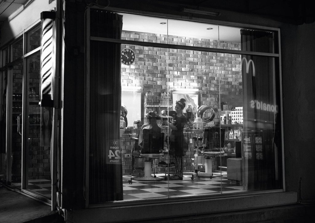 Publicité McDonald's - 24/24h - Reflets - Photo noir&Blanc - Une coiffeuse travaille dans son salon la nuit - Le logo de la marque se reflète sur la devanture - TBWA/DANThailand - Thaïlande - 2016