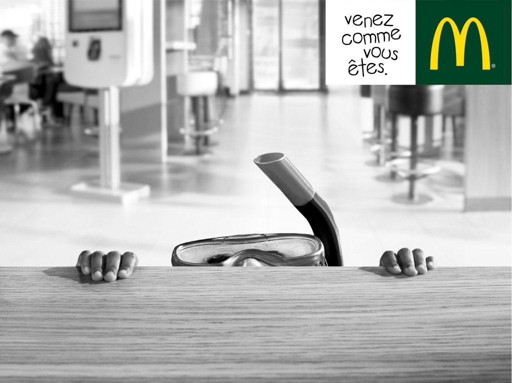 Publicité McDonald's - Venez comme vous êtes - Rentrée des classes - Enfant derrière le comptoir dont on ne voit que les deux mains, son masque et tuba - Noir et blanc - Agence BETC - 2017