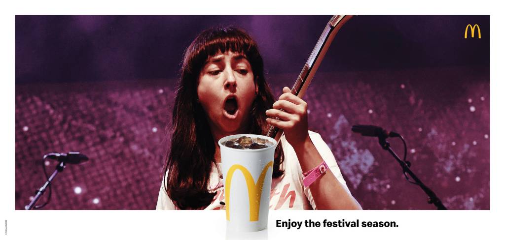 Publicité McDonald's - Enjoy the Festival Season - Une chanteuse avec guitare ouvre la bouche devant un verre de Coca- Agence TBWA - Suisse - 2021